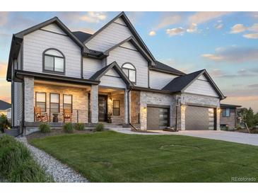 Beautiful two-story home with gray siding, stone accents, a well-manicured lawn, and a basketball hoop on driveway at 27250 E Nova Cir, Aurora, CO 80016