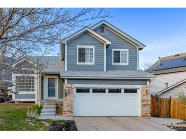Charming two-story home featuring a large garage, blue siding, and well-maintained landscaping at 7586 Halleys Dr, Littleton, CO 80125