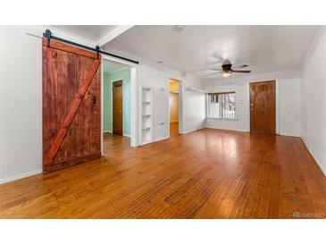 Bright living room with hardwood floors, ceiling fan, and sliding barn door at 2515 Ames St, Edgewater, CO 80214