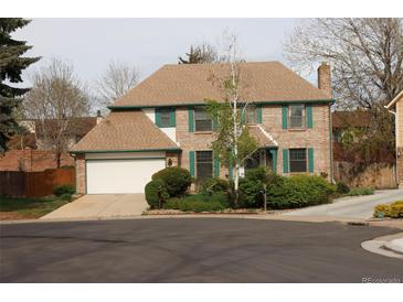 Charming two-story brick home with green shutters, a large garage, and a well-maintained lawn at 12107 E Vassar Dr, Aurora, CO 80014
