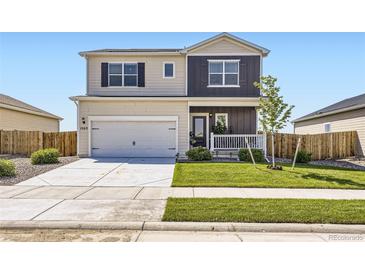 Charming two-story home boasts a manicured lawn, covered porch, and attached two-car garage at 1063 Gianna Ave, Fort Lupton, CO 80621
