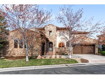 Beautiful stone home featuring a terracotta roof, arched entryway, and a well-manicured lawn at 9151 E Harvard Ave, Denver, CO 80231