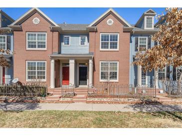 Inviting brick townhome featuring a charming fenced yard and colorful doors at 8381 E 29Th Ave, Denver, CO 80238