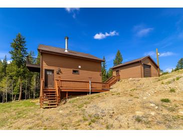 Inviting mountain home featuring wood siding, a charming deck, and separate garage at 33606 Gap Rd, Golden, CO 80403