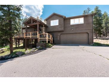 Two-story home with a two-car garage, wood exterior and nicely maintained front yard at 32663 Donna Dr, Conifer, CO 80433