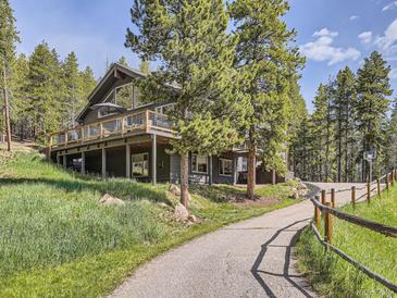 A home's exterior boasts a wrap-around deck with stunning views of the surrounding landscape at 32663 Donna Dr, Conifer, CO 80433