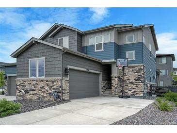 Two-story home featuring gray siding and stone accents, a two-car garage, and a basketball hoop at 6950 Hidden Cove Ct, Castle Pines, CO 80108