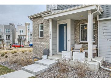 Inviting front porch with blue door, brick accents, and patio seating on well-maintained property at 12345 Festival Ln, Thornton, CO 80241