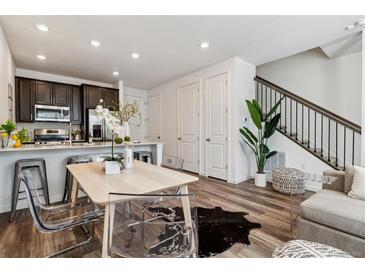 Bright living space with modern table, stylish clear chairs, hardwood floors, and sleek staircase at 2036 S Vance Way, Lakewood, CO 80227