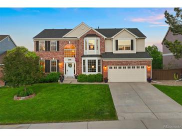 Beautiful brick home with a manicured lawn, a two car garage, and a welcoming front door at 9810 Townsville Cir, Highlands Ranch, CO 80130