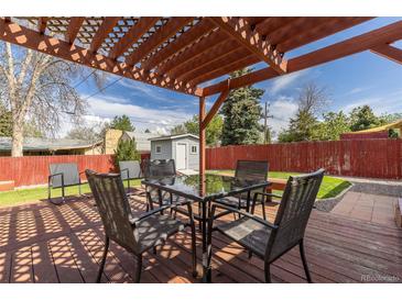Cozy backyard patio with a dining table and chairs underneath a wooden pergola, perfect for outdoor entertaining at 7286 Wolff St, Westminster, CO 80030