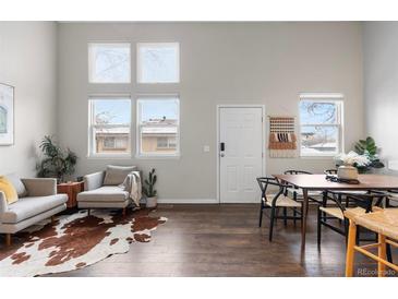 Open-plan living room with high ceilings, large windows, modern furnishings, and wood floors at 6450 W 44Th Pl # B3, Wheat Ridge, CO 80033