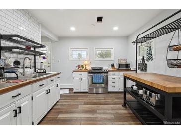 Charming kitchen with white cabinetry, butcher block countertops, stainless steel appliances, and rustic wood flooring at 31551 Black Widow Dr, Conifer, CO 80433
