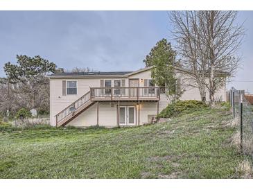 Charming two-story home featuring a wooden deck, grassy yard, and inviting entrance at 1062 Pinon Ln, Elizabeth, CO 80107