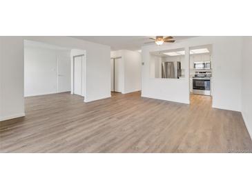 Spacious living room featuring new wood flooring and an open view to the kitchen with stainless appliances at 13992 E Marina Dr # 109, Aurora, CO 80014