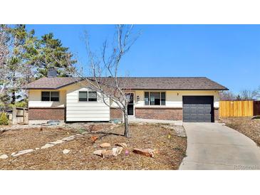 Ranch-style home with a charming brick facade, attached garage, and a well-maintained front yard on a sunny day at 436 Pluto Ct, Lone Tree, CO 80124
