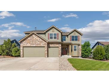 Charming two-story home featuring a stone facade and three-car garage, set under a bright, partly cloudy sky at 42311 Forest Oaks Dr, Elizabeth, CO 80107