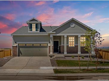 Charming single-Gathering home with a two-car garage, inviting front porch and manicured lawn at dusk at 9069 Pitkin St, Commerce City, CO 80022