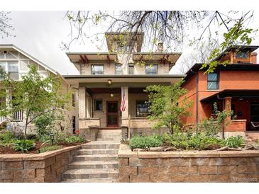 Charming two-story home with brick facade, landscaped front yard, and inviting front porch at 1267 Clayton St, Denver, CO 80206