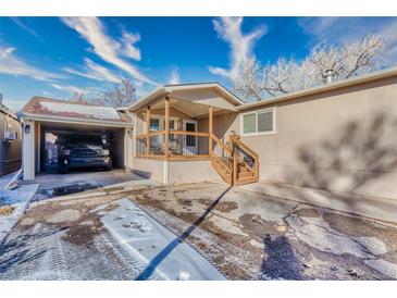 Inviting home featuring a covered porch, convenient carport, and well-maintained yard at 6500 E 88Th Ave # 258, Henderson, CO 80640