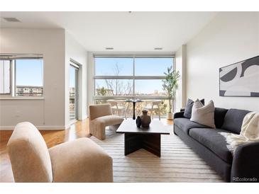 Bright living room featuring modern furnishings, large windows, and hardwood floors at 2958 Syracuse St # 306, Denver, CO 80238