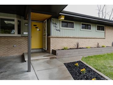 Charming home exterior with a yellow front door, manicured landscaping and mid-century modern design elements at 6530 W 26Th Ave, Edgewater, CO 80214