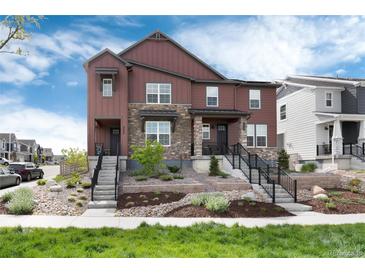 Charming townhome with brown siding, stone accents, and beautifully landscaped front yard at 9804 Rosalee Peak St, Littleton, CO 80125