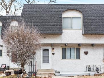 Charming townhome featuring a gray roof and stucco exterior with a quaint front door and manicured landscaping at 421 E Highline Cir, Centennial, CO 80122