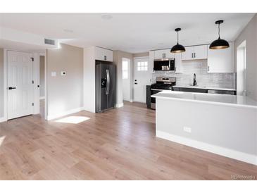 Modern kitchen with stainless steel appliances, white cabinetry, and wood floors at 1568 Verbena St, Denver, CO 80220