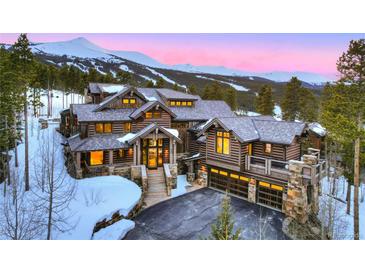 Stunning log home featuring a stone base, grand entrance, and a heated driveway with a backdrop of snow-capped mountains at 422 Timber Trail Rd, Breckenridge, CO 80424