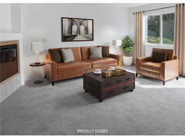 Cozy living room with leather sofa and chair, coffee table and soft natural lighting from large windows at 1339 Sumner St # B, Longmont, CO 80501