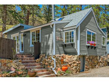 Charming gray home featuring stone accents, brick stairs, and flower boxes under the windows at 27389 Highway 74, Evergreen, CO 80439