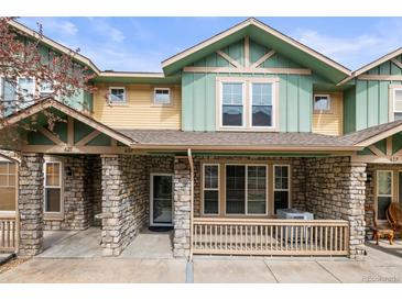 Charming townhome featuring stone accents, a covered front porch and a yellow and green color scheme at 619 S Norfolk Way, Aurora, CO 80017
