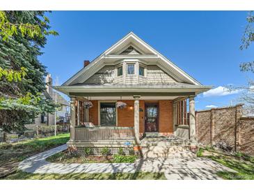 Charming brick home with a welcoming front porch, columns, and beautiful landscaping at 3777 Newton St, Denver, CO 80211