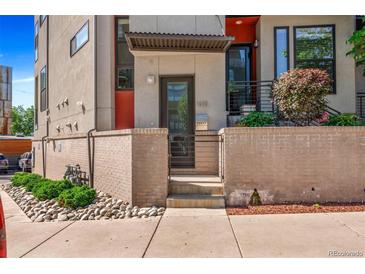 Modern townhome with brick accents, a small gated front yard, and landscaped features at 1932 W 32Nd Ave, Denver, CO 80211