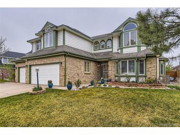 Charming two-story home with brick accents, lush lawn, and an attached two car garage at 5426 S Jasper Way, Centennial, CO 80015