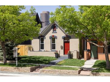 Charming home featuring a well-kept front yard, red door, and beautiful architecture against a downtown skyline at 2355 N Emerson St, Denver, CO 80205
