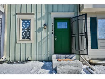 Front view of a charming townhome with a green door and snow-covered landscaping at 1641 S Idalia Cir # F, Aurora, CO 80017