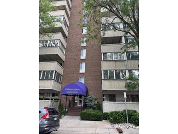 Wellington Square Condominiums shows a brick building with balconies and a blue awning over the entrance at 1888 S Jackson St # 404, Denver, CO 80210