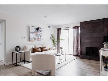 Bright living room with a stone fireplace and sliding glass doors to the outside balcony at 7395 E Eastman Ave # 202N, Denver, CO 80231