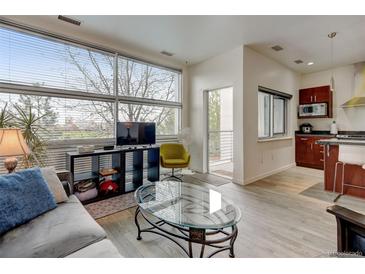 Bright living room featuring hardwood floors, large windows, and an open concept design with a modern kitchen at 2958 Syracuse St # 204, Denver, CO 80238