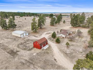Picturesque aerial view of property featuring a charming red barn, house and large shed on sprawling land at 512 County Road 136, Elizabeth, CO 80107