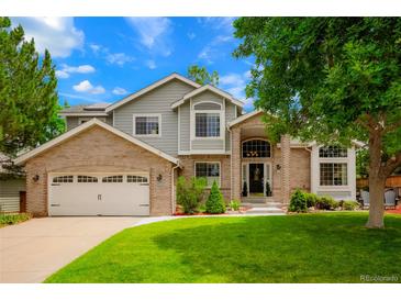 Charming two-story home with a brick facade, lush lawn, and well-maintained landscaping at 2061 Chesapeake Pl, Highlands Ranch, CO 80126