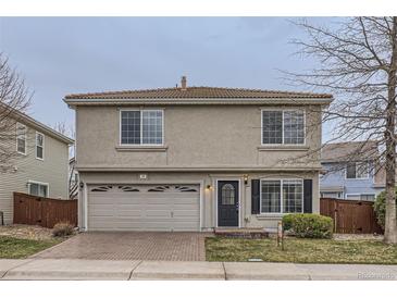 Two-story home with a brick driveway, gray stucco, tile roof, and attached two car garage at 20000 E Mitchell Pl # 39, Denver, CO 80249