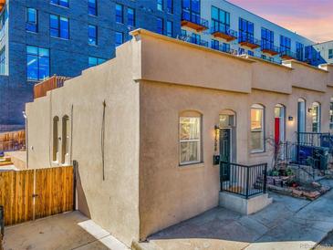 Charming home exterior with a courtyard, light stucco, and wrought iron details. The entry has a new storm door at 2508 Kensing Ct, Denver, CO 80211