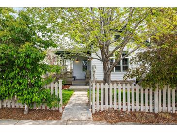 Charming home exterior featuring a well-manicured lawn, mature tree, and inviting white picket fence at 2552 Stonewall Ln, Lafayette, CO 80026