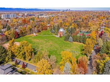 An aerial view showcases a vibrant park with fall foliage, tennis courts, and cityscape views in the background at 2332 S Columbine St, Denver, CO 80210