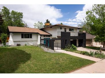 Two-story home with dark brick accents, manicured lawn, and attached carport and front patio area at 7453 E Jefferson Dr, Denver, CO 80237