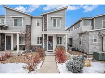 Stylish townhome with gray siding, stone accents, and well-maintained landscaping at 17217 E Exposition Dr, Aurora, CO 80017