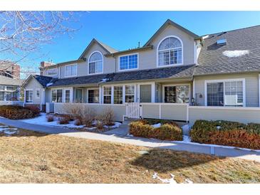 Tan two-story townhome with white trim, small fenced yard, and snow on ground at 1176 E 130Th Ave # C, Thornton, CO 80241